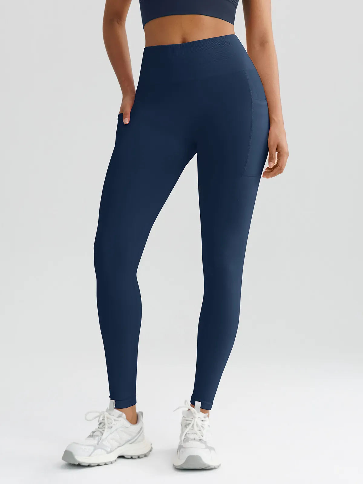 A model wearing a BRXL® B R X L™ Seamless High Waisted Butt-Lifting Leggings with Pockets Charcoal Blue / XS