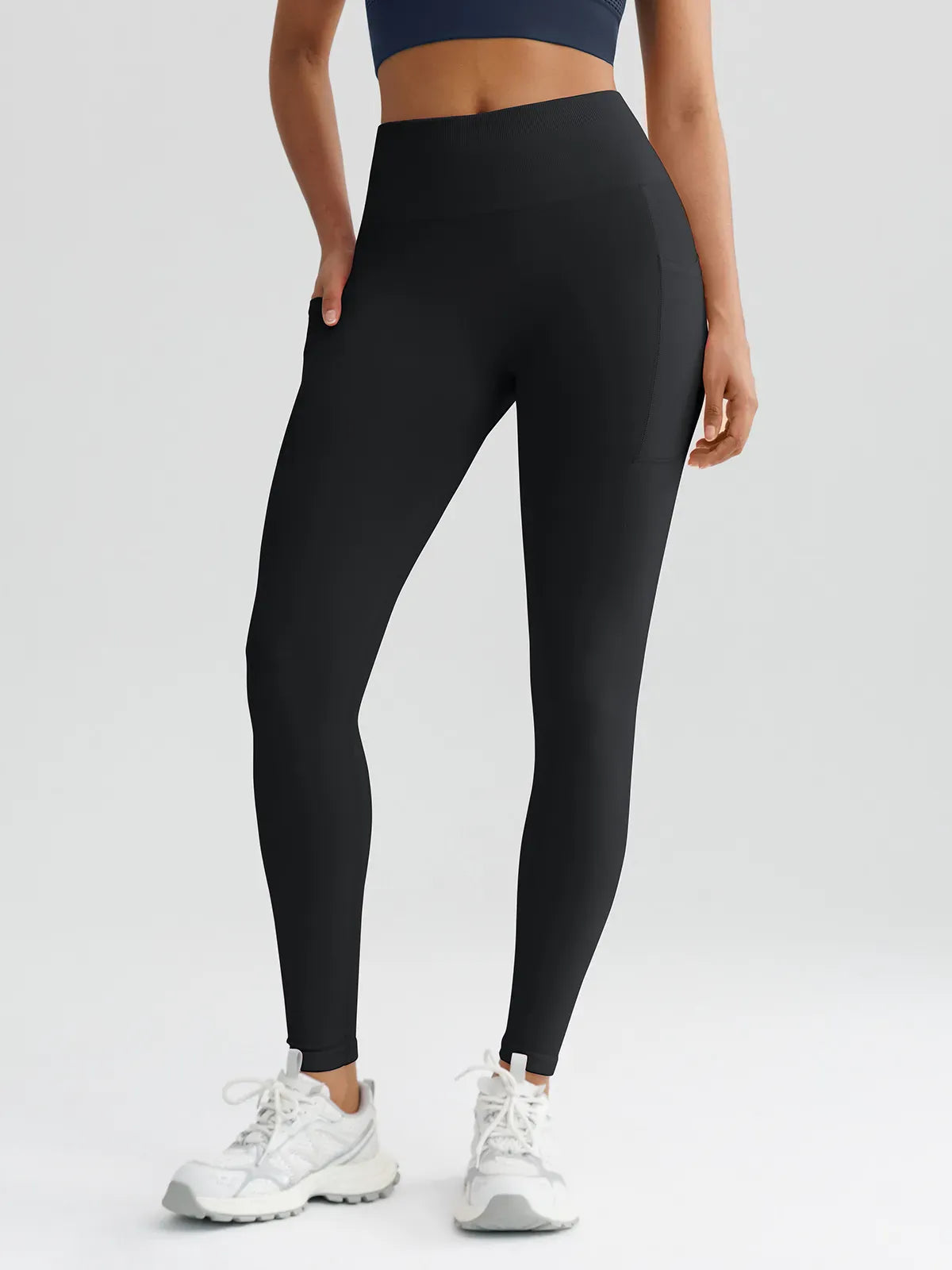 A model wearing a BRXL® B R X L™ Seamless High Waisted Butt-Lifting Leggings with Pockets Black / XS
