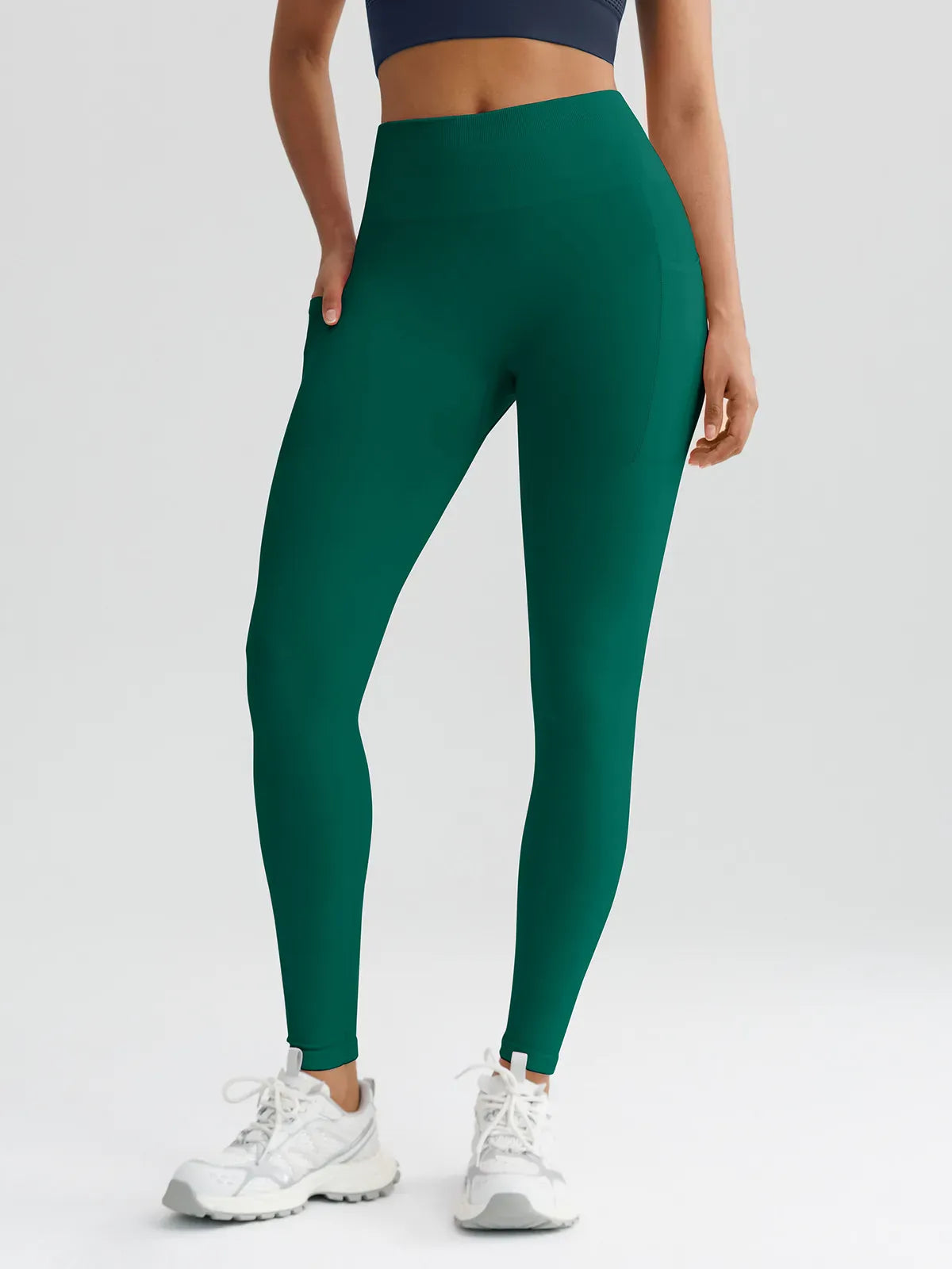 A model wearing a BRXL® B R X L™ Seamless High Waisted Butt-Lifting Leggings with Pockets Dark Green / XS