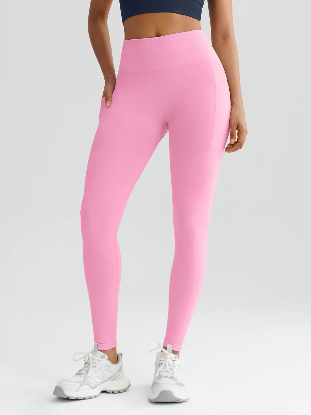 A model wearing a BRXL® B R X L™ Seamless High Waisted Butt-Lifting Leggings with Pockets Baby Pink / XS