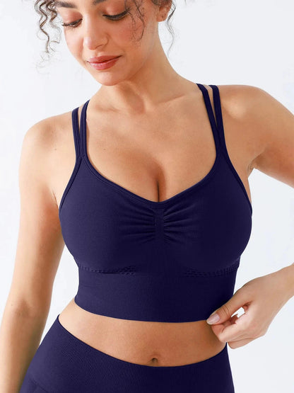 A model wearing a BRXL® Seamless Criss Cross Spaghetti Racerback Sports Bra in Blue / XS