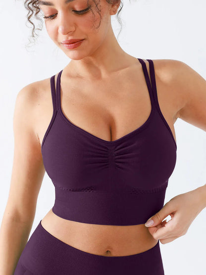 A model wearing a BRXL® B R X L™ Seamless Criss Cross Spaghetti Racerback Sports Bra Dark Plum / XS